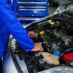 Attentive mechanic examining car engine at repair garage