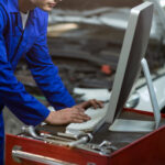 Mechanic working on computer in repair garage