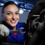 Female mechanic examining car engine at the repair garage